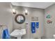 Charming powder room features pedestal sink, decorative mirror, stylish lighting, and coastal-themed decor at 416 Casey Key Rd, Nokomis, FL 34275