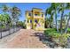 Elegant yellow home features a balcony, brick driveway, lush landscaping and garage at 416 Casey Key Rd, Nokomis, FL 34275