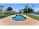 Backyard kidney-shaped pool featuring brick pool deck and black metal fence at 416 Casey Key Rd, Nokomis, FL 34275