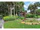 Woodland Park sign with lush greenery and vibrant flowers creating an inviting community entrance at 4326 Brackenwood Ct, Sarasota, FL 34232