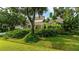 A yellow house surrounded by lush landscaping and mature trees, creating a private and serene setting at 4326 Brackenwood Ct, Sarasota, FL 34232