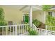 A charming front porch with rocking chairs, potted plants, and a welcoming green front door at 4326 Brackenwood Ct, Sarasota, FL 34232