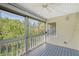 View of screened porch with ceiling fan overlooking lush greenery and a blue wooden floor at 4326 Brackenwood Ct, Sarasota, FL 34232