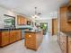 A functional kitchen with wood cabinets, an island, tile floors, and natural light from the dining area at 4917 Hidden Oaks Trl, Sarasota, FL 34232