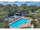 Aerial view of a sparkling pool, hot tub, and tennis courts surrounded by lush trees at 4947 Greencroft Rd # 175, Sarasota, FL 34235