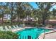 Community pool area with lounge chairs and a serene setting, surrounded by lush greenery and trees at 4947 Greencroft Rd # 175, Sarasota, FL 34235