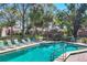 Community pool area with lounge chairs and a serene setting, surrounded by lush greenery and trees at 4947 Greencroft Rd # 175, Sarasota, FL 34235