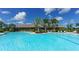 Large community pool surrounded by lounge chairs, palm trees, and beautiful landscaping under a sunny sky at 5424 Cicerone St # 204, Sarasota, FL 34238