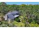 Aerial view capturing the home's exterior with verdant landscaping, private backyard putting green, and surrounding mature trees at 5504 Beneva Woods Circle, Sarasota, FL 34233