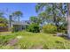 Landscaped backyard featuring mature trees, green grass, and a partial view of the home's unique roofline at 5504 Beneva Woods Circle, Sarasota, FL 34233