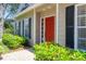 Close-up view of a home's front door, framed by black shutters and lush green bushes at 5504 Beneva Woods Circle, Sarasota, FL 34233