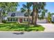 Charming home featuring a landscaped yard, palm trees, black shutters, and a bright red front door at 5504 Beneva Woods Circle, Sarasota, FL 34233