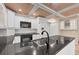 Kitchen with white cabinets, black countertops, and stainless steel sink under a coffered ceiling at 5504 Beneva Woods Circle, Sarasota, FL 34233