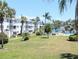 Condo exterior showing manicured lawn, mature palm trees, and view of the community pool at 5901 Garden Ln # H23, Bradenton, FL 34207