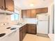 A cozy kitchen featuring wood cabinetry, a double basin sink beneath a window, and white appliances at 5901 Garden Ln # H23, Bradenton, FL 34207