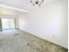 A carpeted, empty living room features a sliding glass door to the outside and a vintage chandelier at 5901 Garden Ln # H23, Bradenton, FL 34207