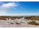 Relaxing beach view: sandy beach with white Adirondack chairs arranged around a small white table at 615 Dream Island Pl # 303, Longboat Key, FL 34228