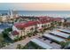 Stunning aerial view of a beachfront condo complex with a red tile roof and beautiful ocean views at sunset at 6236 Midnight Pass Rd # 300, Sarasota, FL 34242
