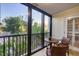 Enclosed lanai with wicker furniture including chairs overlooking lush greenery and water views at 6236 Midnight Pass Rd # 300, Sarasota, FL 34242