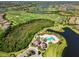 A beautiful aerial view highlights a community clubhouse with a pool, bordering a golf course and a peaceful lake at 7044 Whittlebury Trl, Bradenton, FL 34202