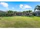 Spacious backyard with lush lawn, palm trees, screened-in lanai, and privacy landscaping at 7044 Whittlebury Trl, Bradenton, FL 34202