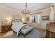 Stylishly furnished bedroom featuring a decorative chandelier, plush rug, and wooden bedside tables at 7044 Whittlebury Trl, Bradenton, FL 34202