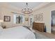 Bright bedroom with a view of the lake and a rustic dresser with decorative artwork above at 7044 Whittlebury Trl, Bradenton, FL 34202