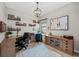Well-lit home office with custom shelves, dark wood floors, and a decorative chandelier at 7044 Whittlebury Trl, Bradenton, FL 34202