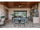 Outdoor kitchen with stainless steel appliances, stone accents, and covered patio with a ceiling fan and dining table at 7044 Whittlebury Trl, Bradenton, FL 34202