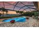 Inviting screened-in pool area with beautiful landscaping and scenic lake views at sunset at 7044 Whittlebury Trl, Bradenton, FL 34202