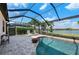 Pool area with screened enclosure, lounge chairs, lake view, and lush landscaping surrounding the patio at 7044 Whittlebury Trl, Bradenton, FL 34202