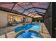 Screened-in pool area at sunset featuring a kidney shaped pool, jacuzzi, brick pavers, and covered patio with seating at 7044 Whittlebury Trl, Bradenton, FL 34202