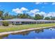 Waterfront condo exterior with lush landscaping and screened lanai overlooking serene pond at 7069 W Country Club N Dr # 7069, Sarasota, FL 34243