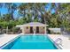 Community pool with blue water, poolside building, and lounging space surrounded by mature trees at 7069 W Country Club N Dr # 7069, Sarasota, FL 34243