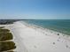 Beautiful aerial shot of the beach with white sand, blue water, and people enjoying the sun at 717 Treasure Boat Way, Sarasota, FL 34242