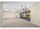 A spacious living room with neutral carpeting, chandelier, and large sliding doors to a screened in patio at 717 Treasure Boat Way, Sarasota, FL 34242