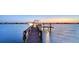 Waterfront property featuring a private boat dock with a boat at sunset, offering scenic views and direct water access at 7342 Captain Kidd Ave, Sarasota, FL 34231