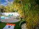 Entertainment area with a shimmering pool, lawn games, lounge seating, and lush tropical landscaping at 811 Jacaranda Rd, Anna Maria, FL 34216
