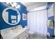 Bright bathroom with round mirror, white vanity, and blue walls creates a fresh, coastal feel at 811 Jacaranda Rd, Anna Maria, FL 34216