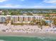 Aerial view of a beachfront hotel and beach with palm trees and clear water at 915 Seaside Dr # 405 Weeks 22-23, Sarasota, FL 34242