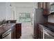 Galley-style kitchen featuring stainless steel appliances, dark cabinetry, and a view of the serene backyard and lake at 11319 82Nd E St, Parrish, FL 34219