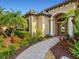 Inviting front entrance with stone walkway, beautiful landscaping, and an arched entryway at 13644 Brilliante Dr, Venice, FL 34293