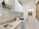 Laundry room with white cabinets above the washer and dryer and a utility sink, next to a doorway at 13644 Brilliante Dr, Venice, FL 34293