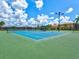 Active lifestyle featuring community tennis court with bright blue surface amidst lush landscaping at 13644 Brilliante Dr, Venice, FL 34293