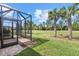 Screened patio with doorway that leads to the backyard with manicured lawn and palm trees at 17640 Northwood Pl, Bradenton, FL 34202