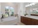 Bright bathroom featuring a soaking tub, large window, dual sinks, and vanity at 2309 Chardonnay Ter, Parrish, FL 34219