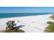 Aerial view of a wide beach with white sand, blue ocean, and various beachgoers enjoying the sunny day at 2350 Novus St, Sarasota, FL 34237