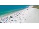 Overhead shot of a crowded beach with white sand, turquoise water, umbrellas, and beachgoers relaxing in the sun at 2350 Novus St, Sarasota, FL 34237