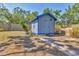 Backyard shed with blue trim on a sunny day surrounded by grassy area and palm trees at 2350 Novus St, Sarasota, FL 34237