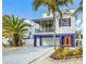 Charming elevated two-story home with a vibrant orange front door and lush landscaping at 316 64Th St, Holmes Beach, FL 34217